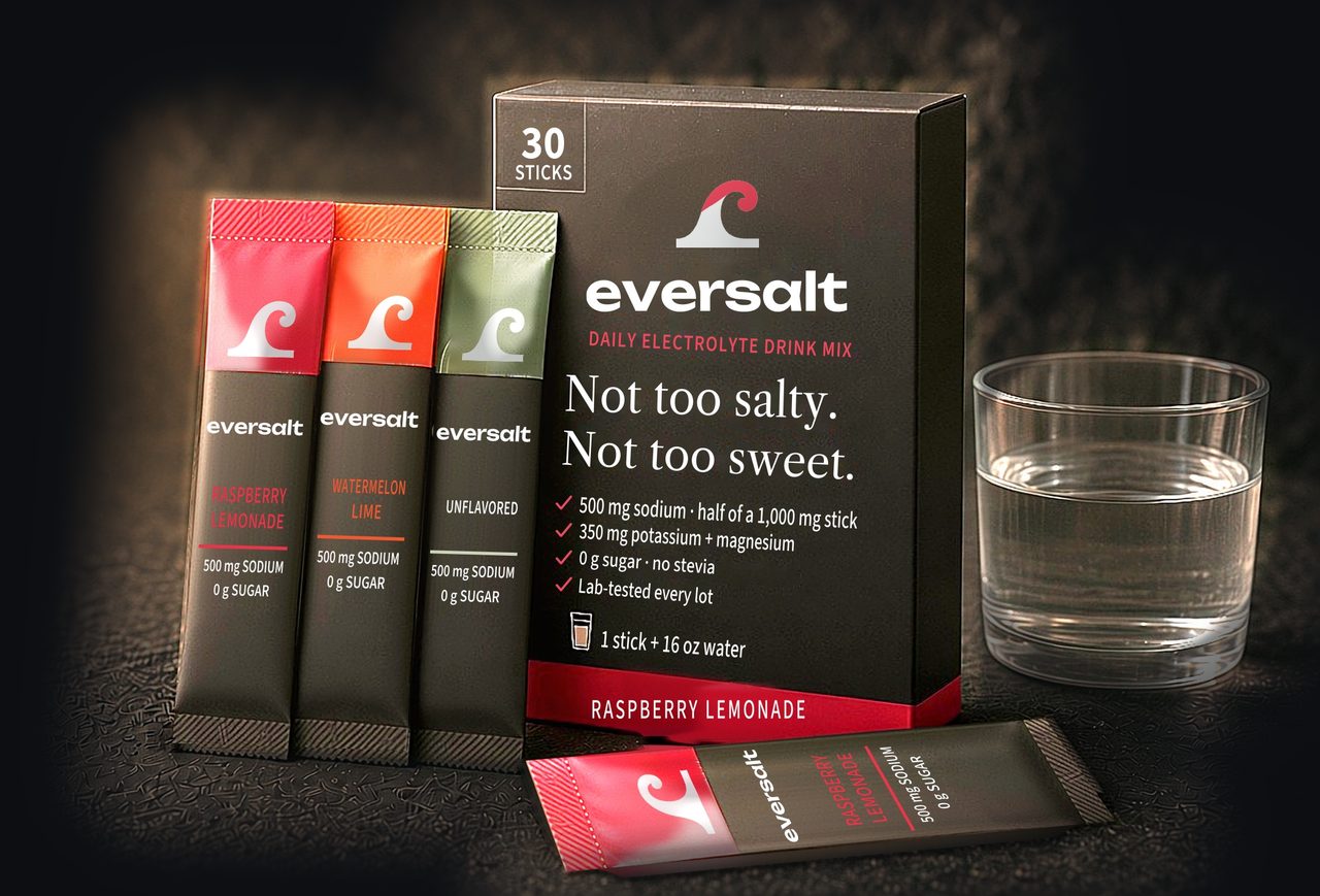 eversalt electrolyte drink mix: a 30-stick box of Raspberry Lemonade with Raspberry Lemonade, Watermelon Lime and Unflavored stick packs, each marked 500 mg sodium and 0 g sugar, beside a glass of water